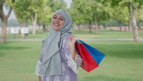 Mujer-Musulmana-Feliz-Posando-Con-Bolsas-De-Compras-En-El-Parque