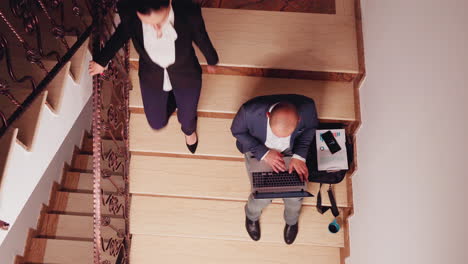 Top-view-of-company-manager-doing-research-sitting-on-stair