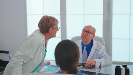 Mature-woman-doctor-talking-about-patient-diagnosis-during-meeting