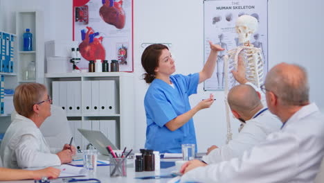 Medizinische-Junge-Krankenschwester-Präsentiert-Wirbelsäulenanatomie-Mit-Menschlichem-Skelettmodell