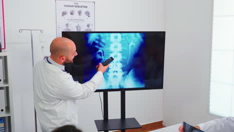 Expert-doctor-holding-medical-training-pointing-on-digital-x-ray