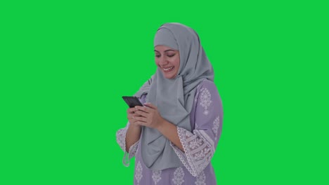 Glückliche-Muslimische-Frau,-Die-Auf-Dem-Grünen-Bildschirm-Des-Telefons-Tippt