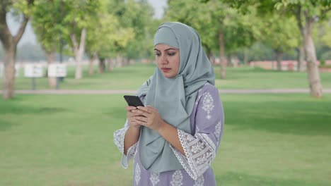 Muslimische-Frau-Tippt-Im-Park-Am-Telefon