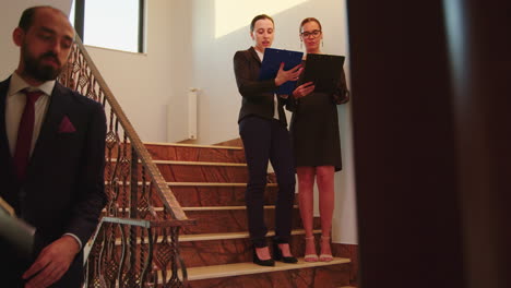 Woman-colleagues-talking-standing-on-stairs