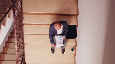 Top-view-of-entrepreneur-reading-financial-statistics-from-clipboard