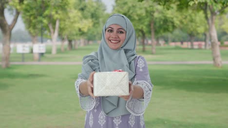 Mujer-Musulmana-Feliz-Dando-Un-Regalo-En-El-Parque