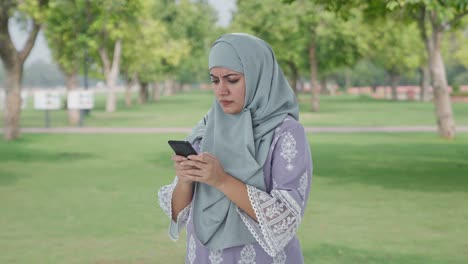 Mujer-Musulmana-Enojada-Escribiendo-Por-Teléfono-En-El-Parque