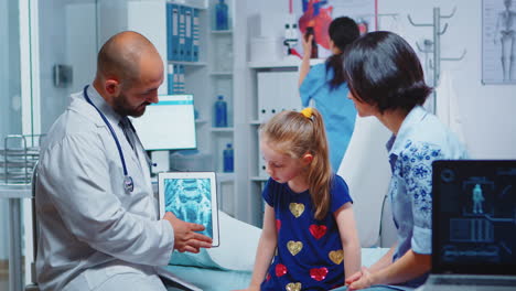 Male-pediatrician-checking-bone-X-ray-on-tablet