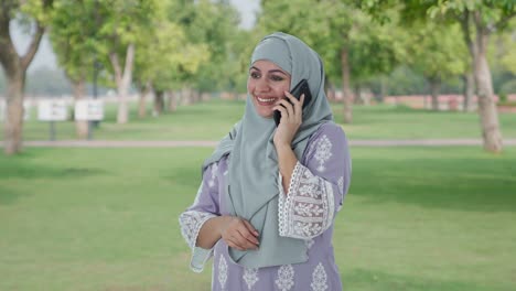 Mujer-Musulmana-Feliz-Hablando-Por-Teléfono-En-El-Parque