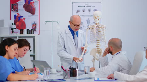 Oberarzt-Präsentiert-Die-Arbeit-Der-Menschlichen-Hand-Am-Skelettmodell