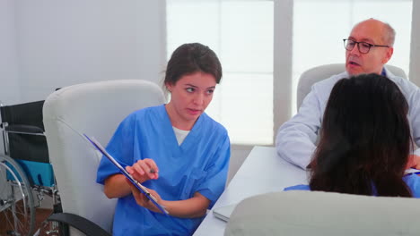 Female-nurse-holding-clipboard-explaining-diagnosis