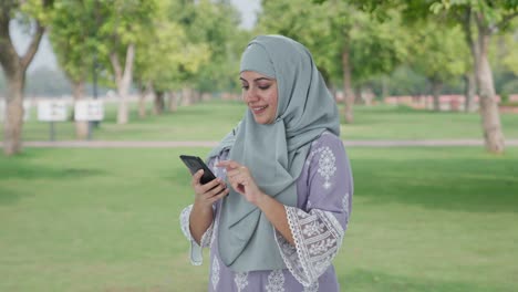 Mujer-Musulmana-Feliz-Usando-El-Teléfono-En-El-Parque