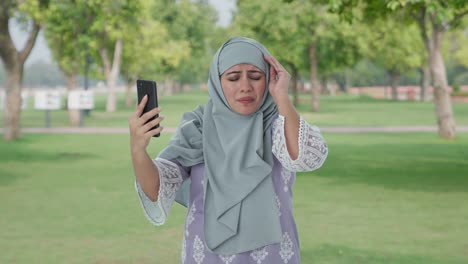 Mujer-Musulmana-Enojada-Hablando-Por-Videollamada-En-El-Parque
