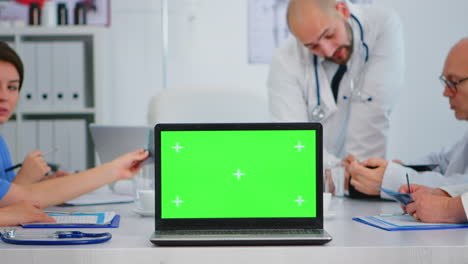 Group-of-doctors-placing-laptop-with-chroma-key-in-front-of-camera