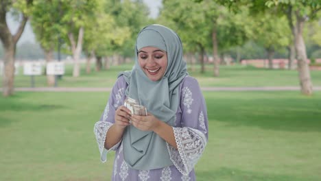 Glückliche-Muslimische-Frau,-Die-Im-Park-Geld-Zählt