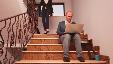 Office-executive-sitting-on-stair-typing-on-laptop