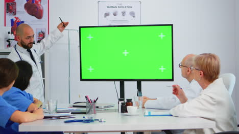 Doctor-explaining-meeting-topics-by-previewing-on-a-green-screen-monitor