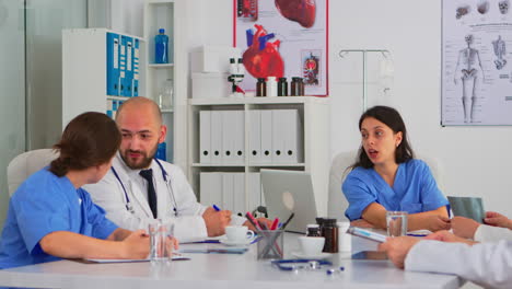 Team-of-doctors-during-brainstorming-sitting-at-desk-in-meeting-medical-office
