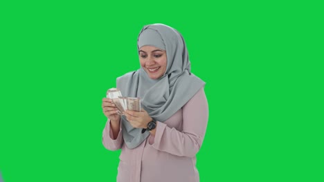 Happy-Muslim-businesswoman-counting-money-Green-screen