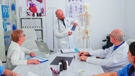 Doctor-explaining-radiography-in-front-of-medical-staff-using-skeleton