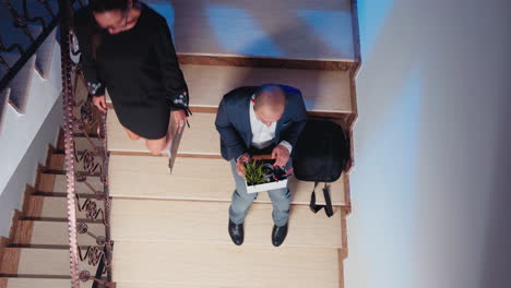 Top-view-of-businessman-getting-fired-sitting-on-staircase