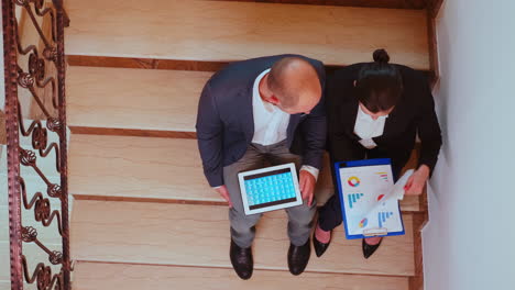 Top-view-of-colleagues-working-on-stairs-using-tablet
