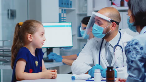 Doctor-Hablando-Con-Un-Niño-Usando-Máscara-De-Protección