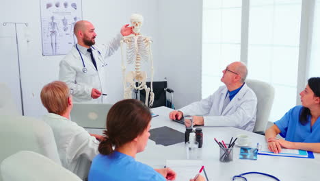 Expert-radiologist-demonstrating-on-skeleton-during-briefing