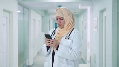 Médico-Musulmán-Enojado-Enviando-Mensajes-A-Alguien-Por-Teléfono