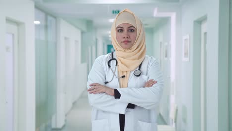 Médico-Musulmán-Confiado-De-Pie-Con-Las-Manos-Cruzadas