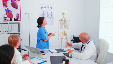 Assistent-pointing-on-skeleton-in-front-of-medical-stuff
