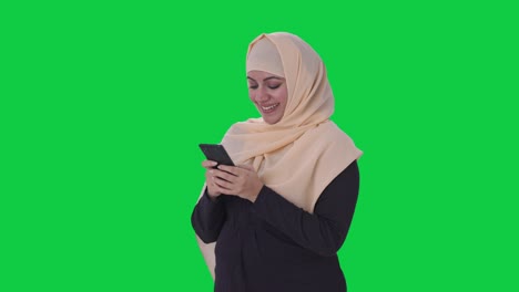 Glückliche-Muslimische-Frau,-Die-Auf-Dem-Grünen-Bildschirm-Des-Telefons-Chattet