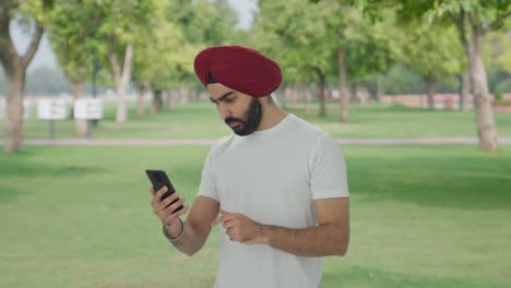 Sikh-Indian-man-scrolling-phone-in-park