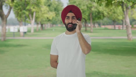 Fröhlicher-Sikh-Indianer,-Der-Im-Park-Telefoniert-Und-Lächelt