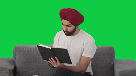 Curious-Sikh-Indian-man-reading-book-and-drinking-tea-Green-screen