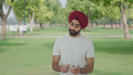 Trauriger-Sikh-Indianer,-Der-Im-Park-Geld-Zählt