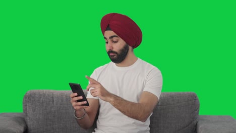 Sleepy-Sikh-Indian-man-using-mobile-phone-Green-screen