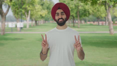 Glücklicher-Sikh-Indianer,-Der-Im-Park-Ein-Siegeszeichen-Zeigt