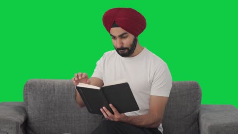 Happy-Sikh-man-reading-book-and-drinking-tea-Green-screen