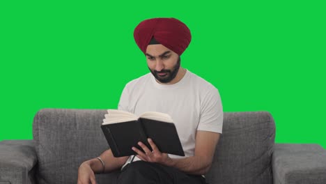 Fröhlicher-Sikh-Indianer,-Der-Ein-Buch-Liest-Und-Tee-Auf-Grünem-Bildschirm-Trinkt