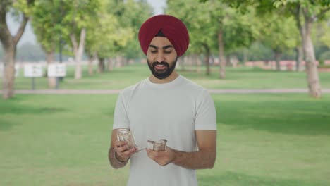 Glücklicher-Sikh-Indianer,-Der-Im-Park-Geld-Zählt