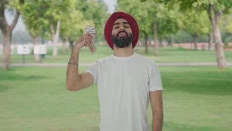 Happy-Sikh-Indian-man-using-money-as-fan-in-park