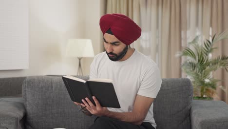 Curious-Sikh-Indian-man-reading-book-and-drinking-tea
