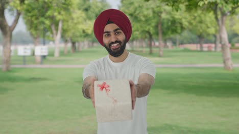 Glücklicher-Sikh-Indianer,-Der-Im-Park-Ein-Geschenk-Macht