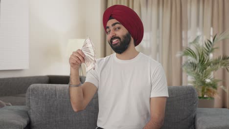 Egoistic-Sikh-Indian-man-using-money-as-fan