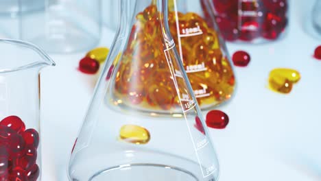 Seamless-looping-shot-with-red-and-yellow-gel-capsules-inside-laboratory-glassware-isolated-on-a-clean-white-surface.-Close-up-of-vitamin-supplement.-Healthy-lifestyle,-diet,-omega-3,-fish-oil-concept