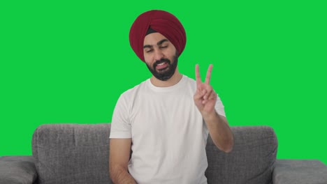 Fröhlicher-Sikh-Indianer-Zeigt-Siegeszeichen-Auf-Grünem-Bildschirm