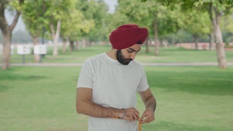 Triste-Hombre-Indio-Sikh-Midiendo-La-Cintura-Usando-Cinta-De-Pulgada-En-El-Parque