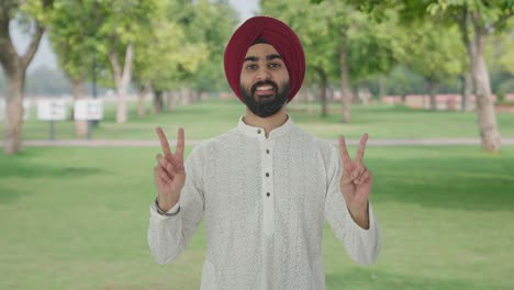 Glücklicher-Sikh-Indianer,-Der-Im-Park-Ein-Siegeszeichen-Zeigt