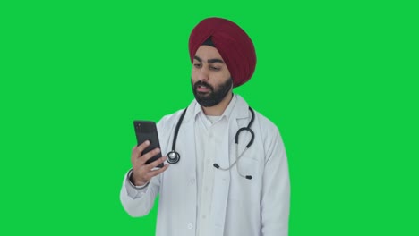 Seriöser-Indischer-Sikh-Arzt,-Der-über-Einen-Videoanruf-Mit-Grünem-Bildschirm-Spricht